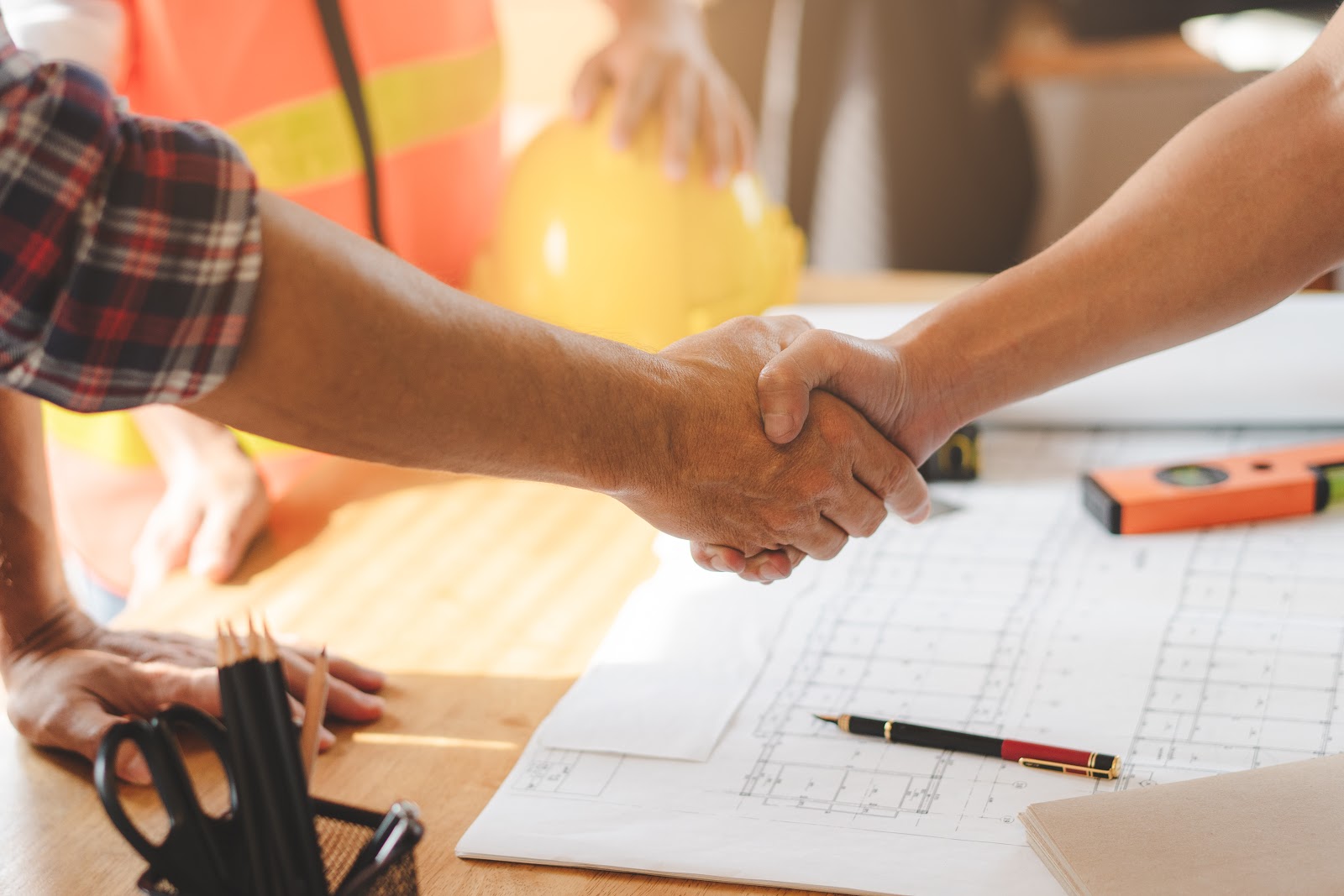 Expanding Into Different Types of Projects Successful deal, male architect shaking hands with client in construction site after confirm blueprint for renovate building.